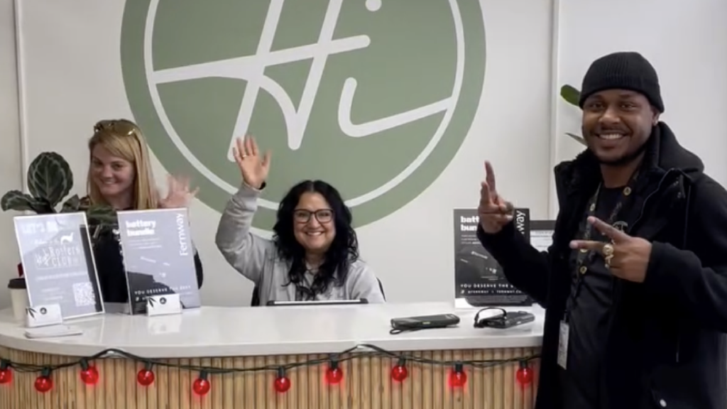 High Street Dispensary staff smiling and waving from behind the reception desk, spreading positivity and friendly vibes.