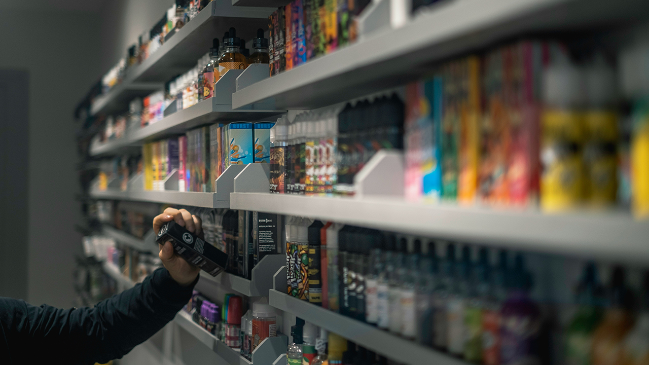 Customer reaching for vape accessories on a shelf at a Hackettstown smoke shop