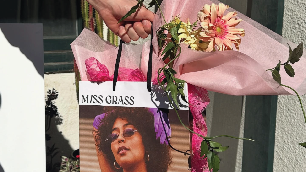 Miss Grass gift bag with pink tissue paper, flowers, and cannabis-themed Mother's Day packaging.