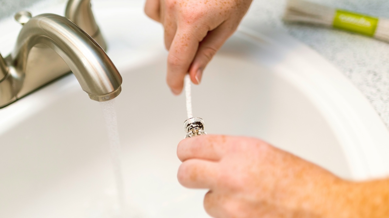 Cleaning a cannabis pipe with pipe cleaner under running water